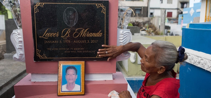 Elvira Miranda lovingly touches the grave of her son, Leover, killed in the Philippines drug wars. Image by Amanda Mustard