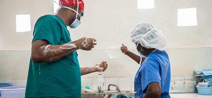 A nurse pours water from a pitcher to help the surgeon scrub for a cesarean section at St. Therese Hospital in Central Plateau, Haiti. © 2014 C. Hanna-Truscott/Midwives for Haiti, Courtesy of Photoshare