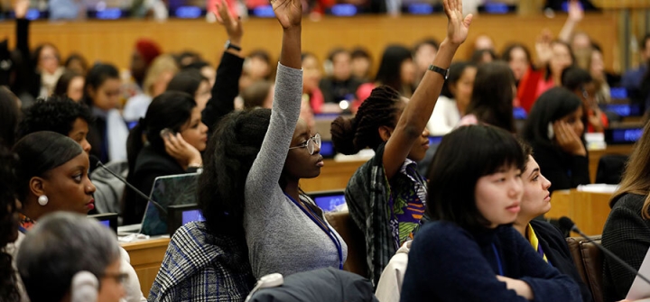 Women raising their hands at a UN Women event for young leaders.