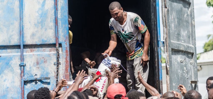 A man gives a bag of rice to a crowd of earthquake victims gathered for the distribution of food and water at the "4 Chemins" crossroads in Les Cayes, Haiti on August 20, 2021. 