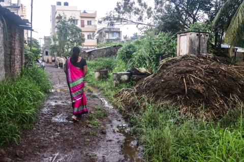ASHA Shubhangi Kamble walking through a dirty patch of mud during heavy rainfall to a community member’s house whose child fell sick. 