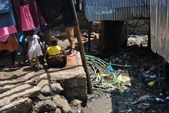 Children play next to a raw sewage drainage at Maili Saba village in Nairobi's Kibera slums on October 12, 2020