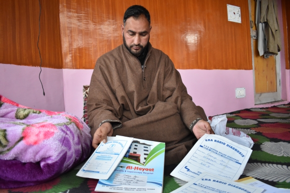 Javed Ahmed Padroo displays paperwork provided by the hospital where his wife died soon after giving birth to 2 stillborn sons. Anantnag, Kashmir, April 21. 