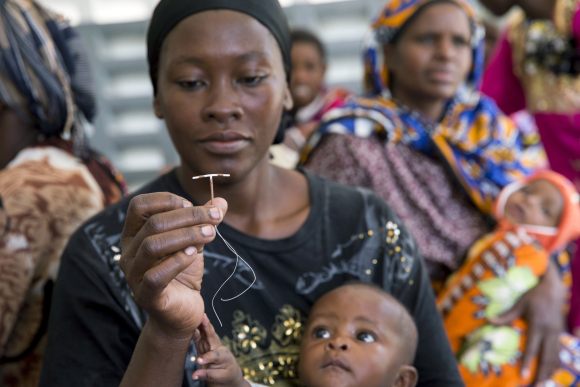 A woman holds up a contraceptive implant during Marie Stopes mobile clinical outreach team visit to a hospital in Rabai, Kenya. June 16, 2014.