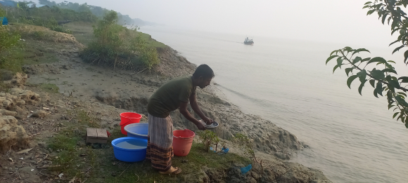 Mohammad Sheikh, who survived a tiger attack 7 years ago, washes dishes on the bank of Pashur river on Jan. 1, 2023. Photo by Ritwika Mitra