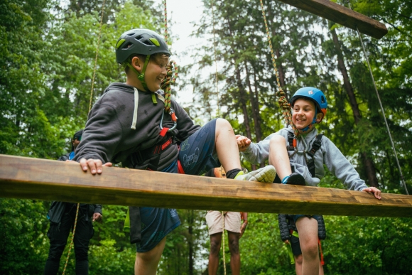 2 young campers wearing helmets step onto a wood beam at Camp Ho Mita Koda
