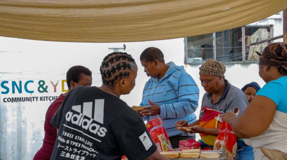 A group of unemployed mothers volunteer at a community soup kitchen that helps them feed their children.