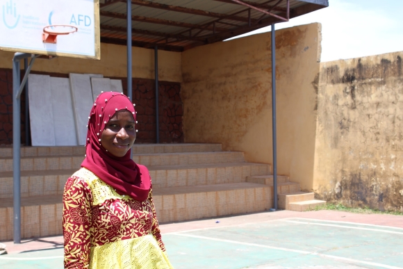 Haja Abibatu Jalloh, wearing a red and yellow dress and red head scarf, stands in front of one of SLPH's newly renovated outdoor recreational facilities.