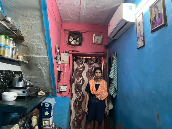 Maya Devi stands next to her air conditioning unit.