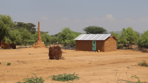 An ant hill rises taller than a nearby single story home in Loima, Turkana.