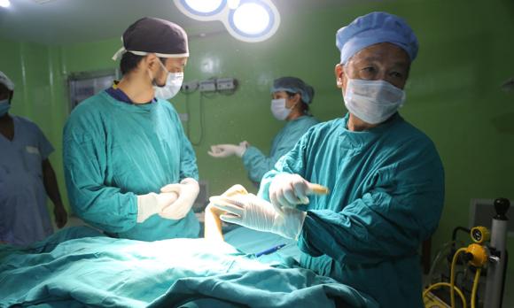 Dr. Shankar Man Rai in the OR in Nepal, helping a young burn patient.