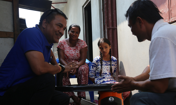 Saraswoti looks on as her family gets instructions on a new, safer model of cookstove.