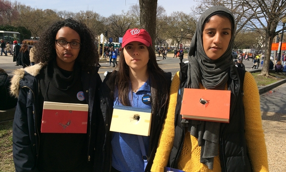 Hermela Assefa, Sophie Hernandez and Mararfi Badr (l to r), wear bullet-pierced books created by friend Noah Taylor. “Books are made for learning but classrooms are battlefields and should not [have to] be used as shields,” says Badr.